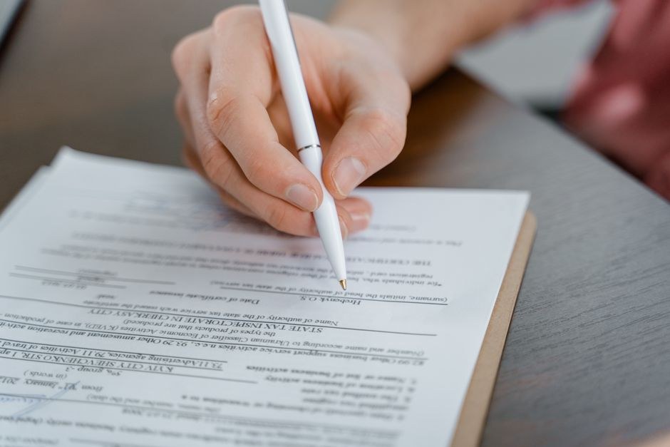 A person writing notes on a document at a desk during the editorial process.