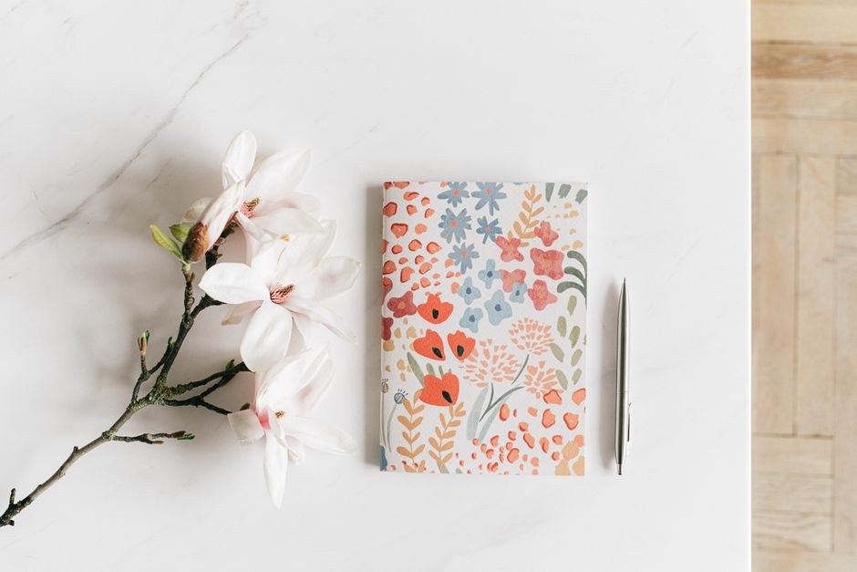 Editorial notebook and flowers on a light desk